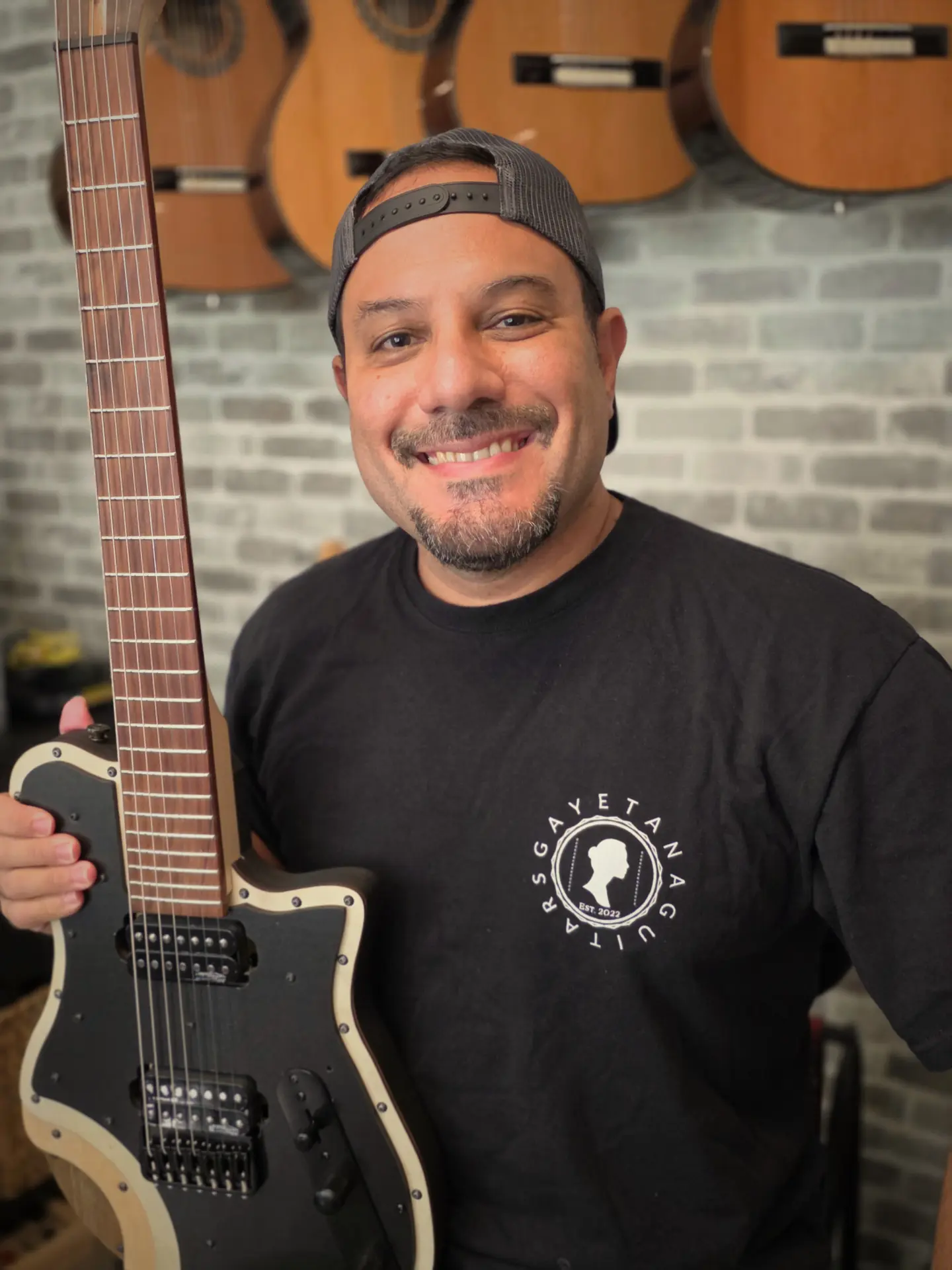 Roberto "ATTO" Castro holding a SieteQuinto seven-string guitar in his studio